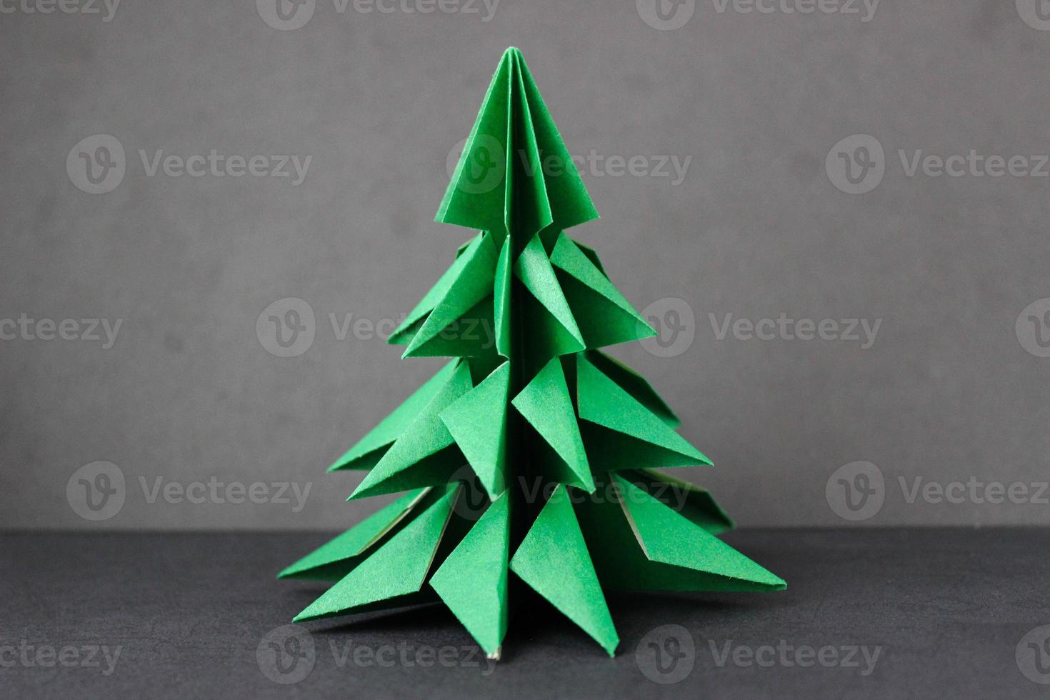 árbol verde de origami sobre un fondo negro foto