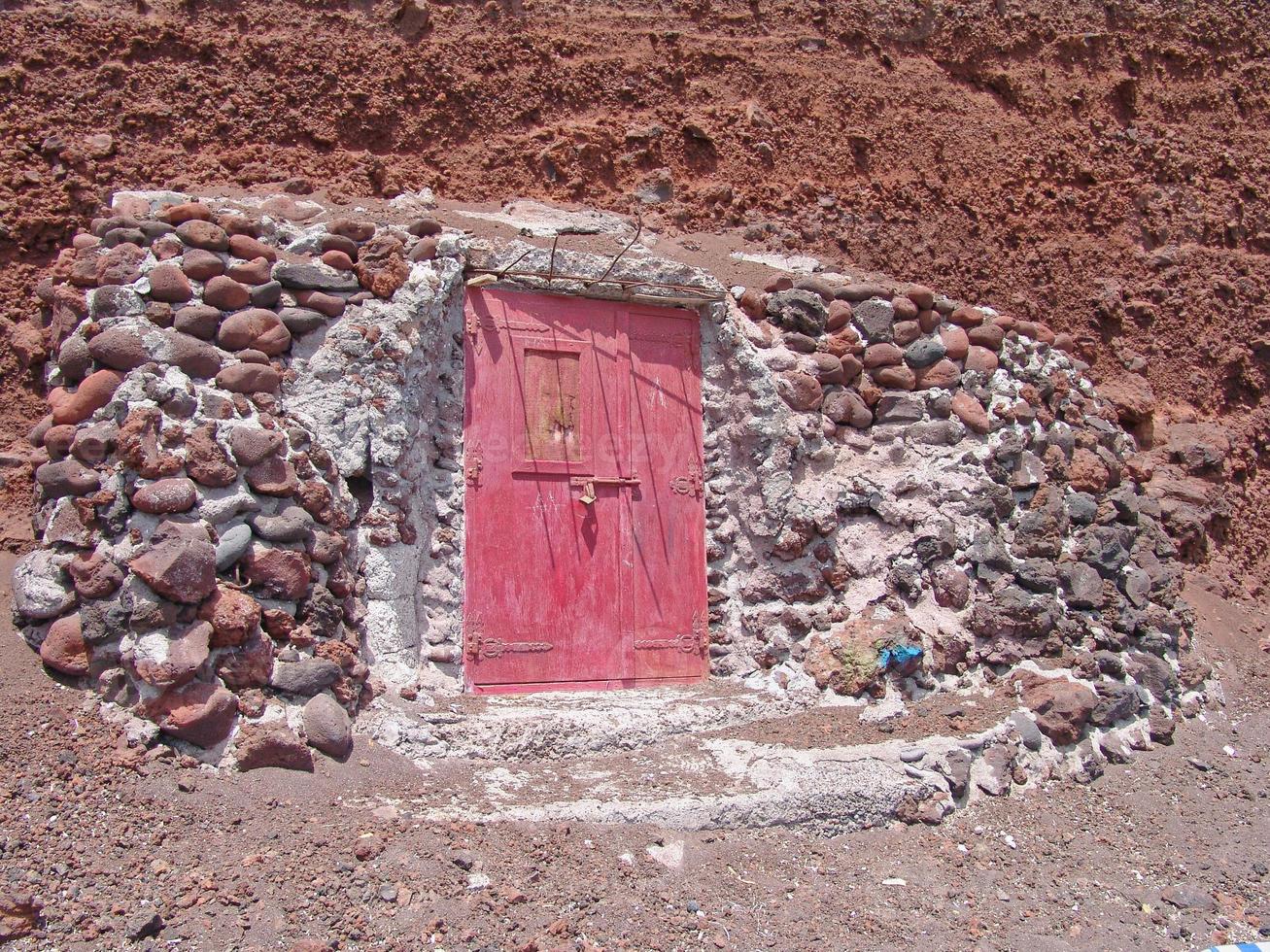 Door with stones in red beach of Santorini Greece photo