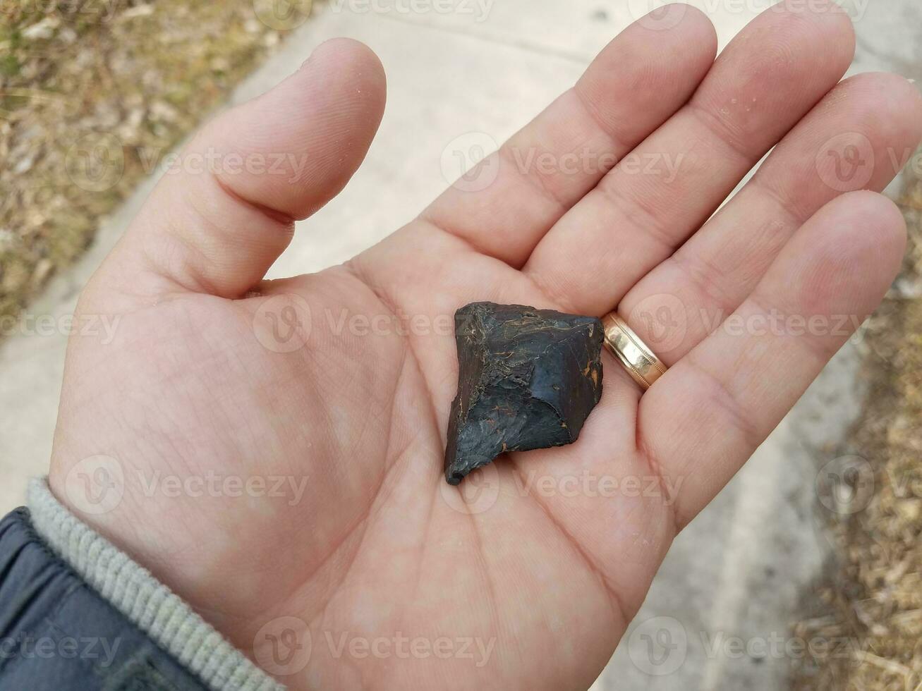 hand holding black burnt piece of wood over cement photo