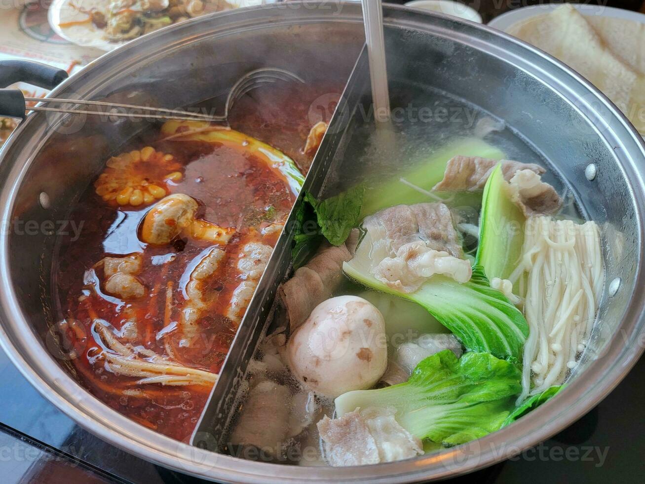 Chinese hot pot with spicy and regular broth and meat and vegetables photo