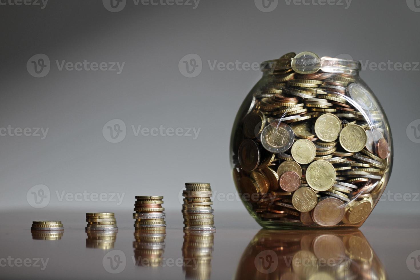 crecientes montones de monedas que terminan en un frasco de vidrio lleno de dinero - inflación o estrategia de inversión exitosa foto