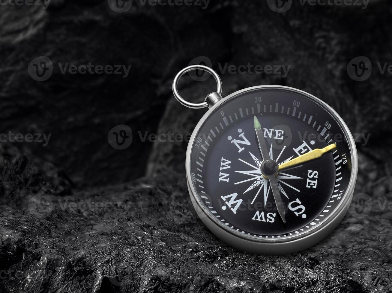 Compass nestled on black coal background. Travel destination and navigation concept photo
