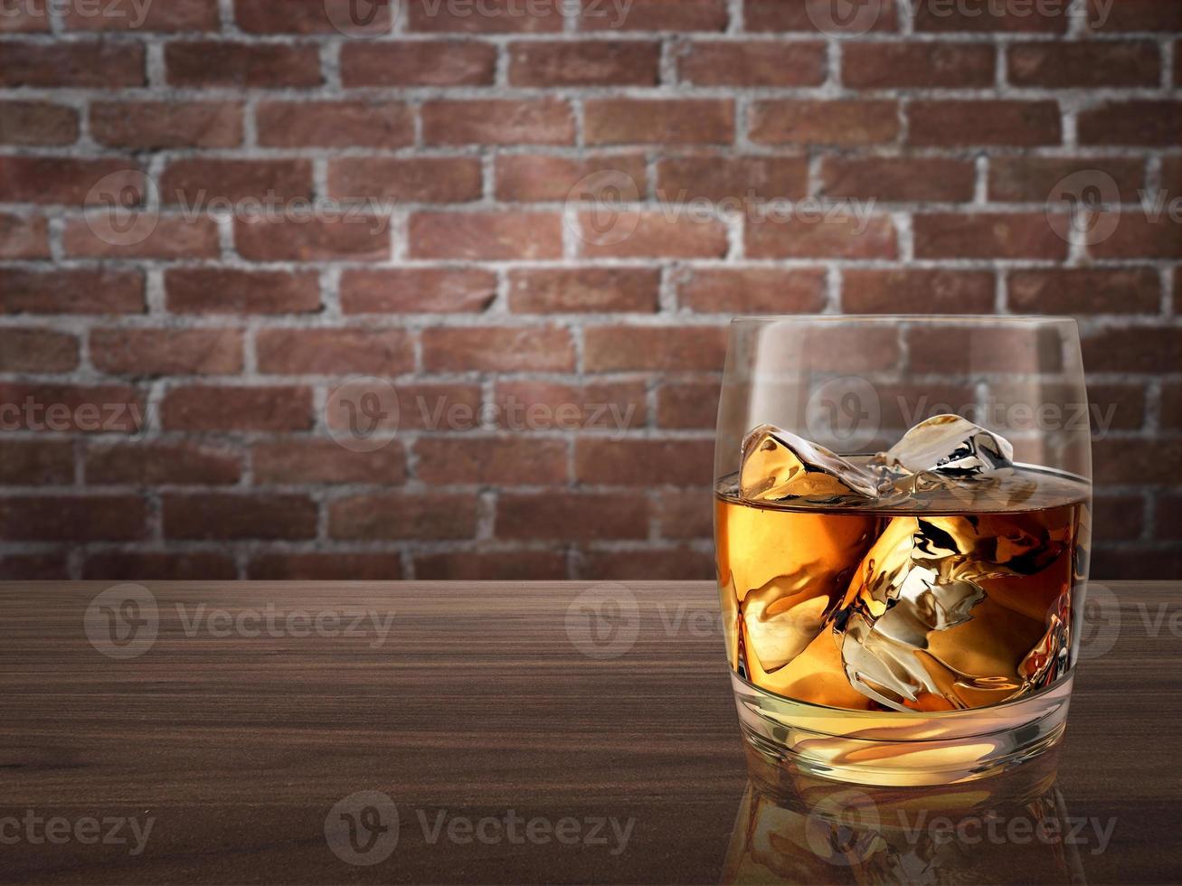 whiskey glass on wood counter red brick background photo