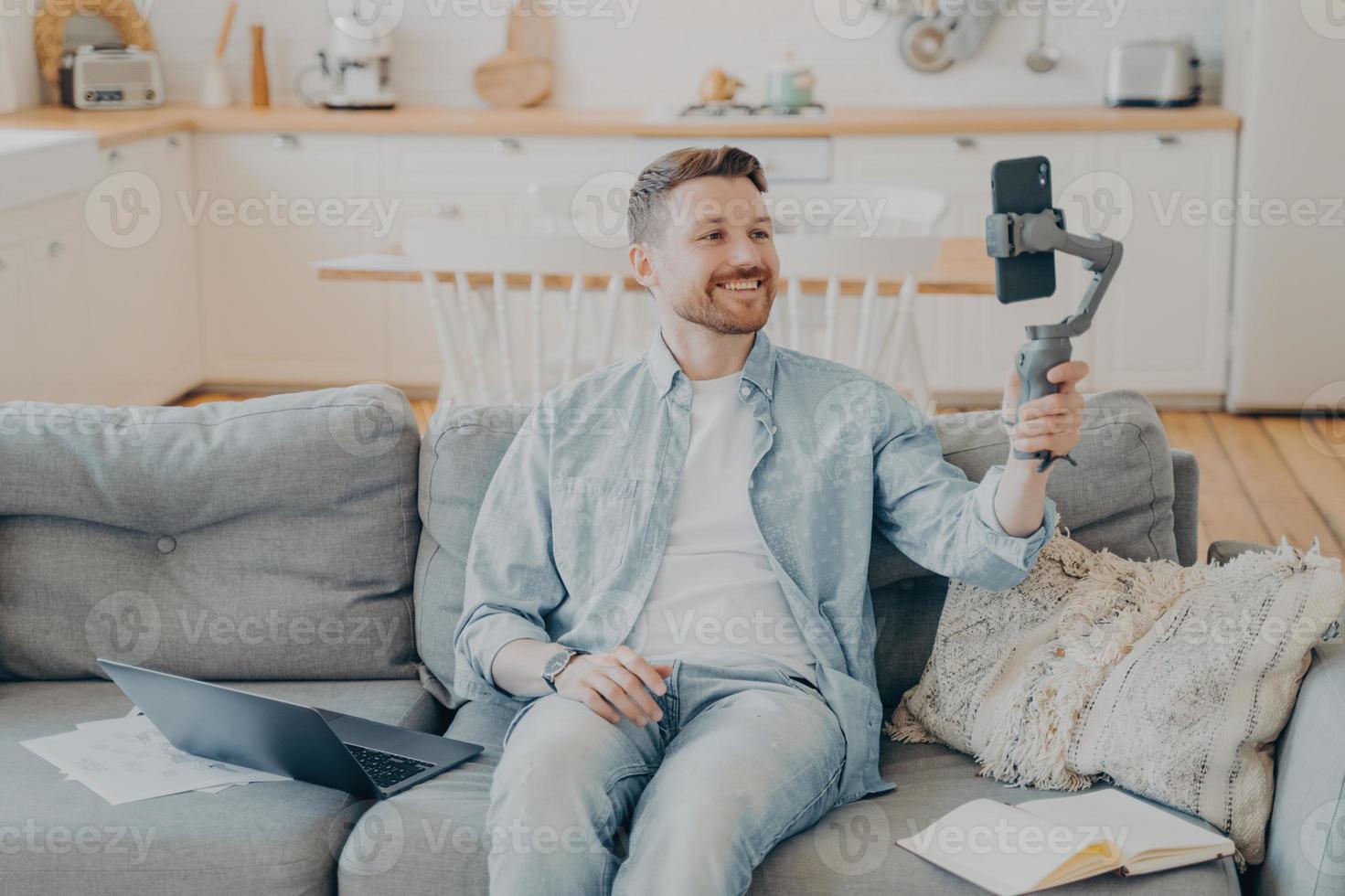 Young man in video call with friend while sitting on couch photo