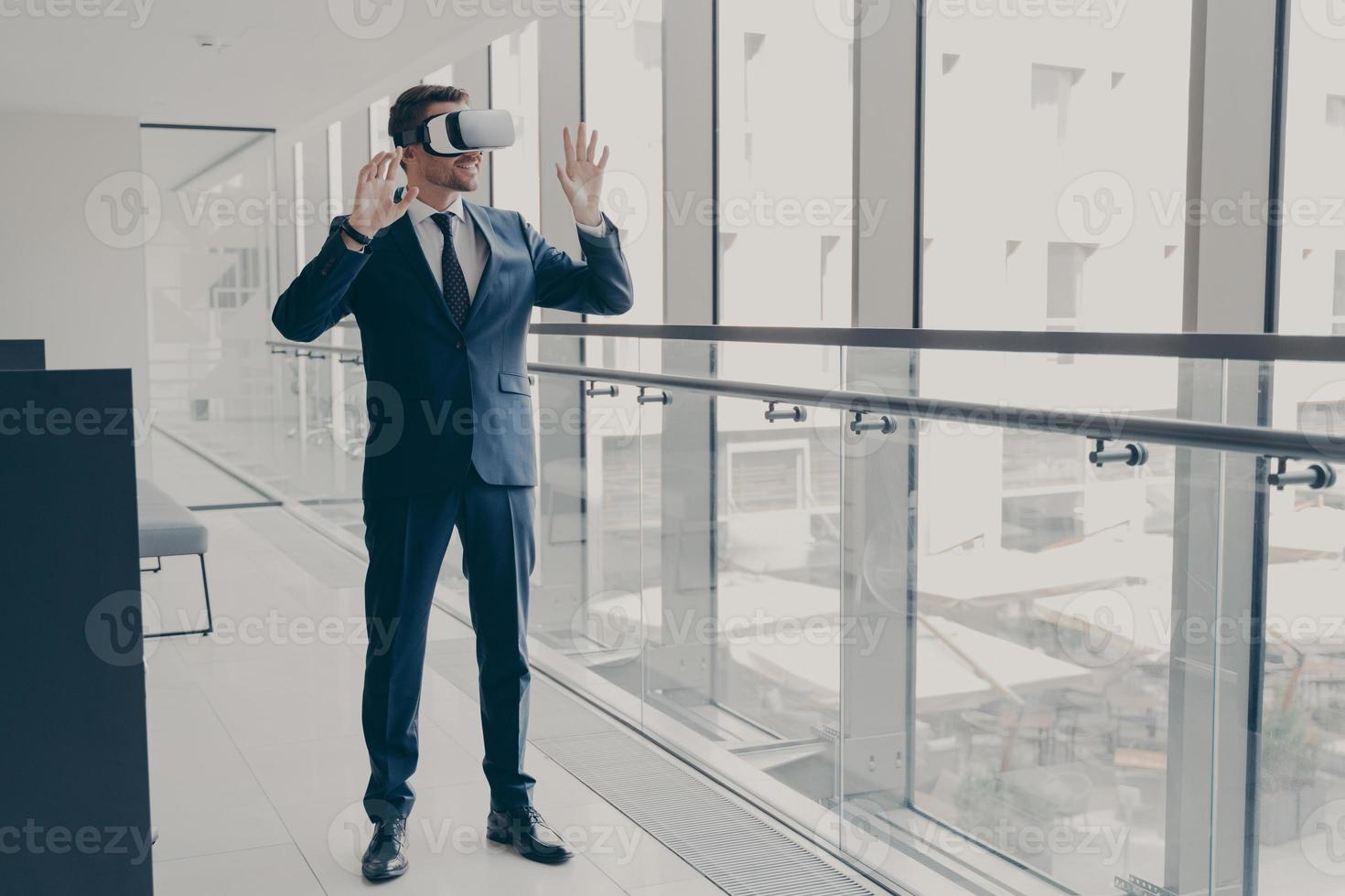 Successfu business professional in elegant suit standing in office and using VR technologies at work photo