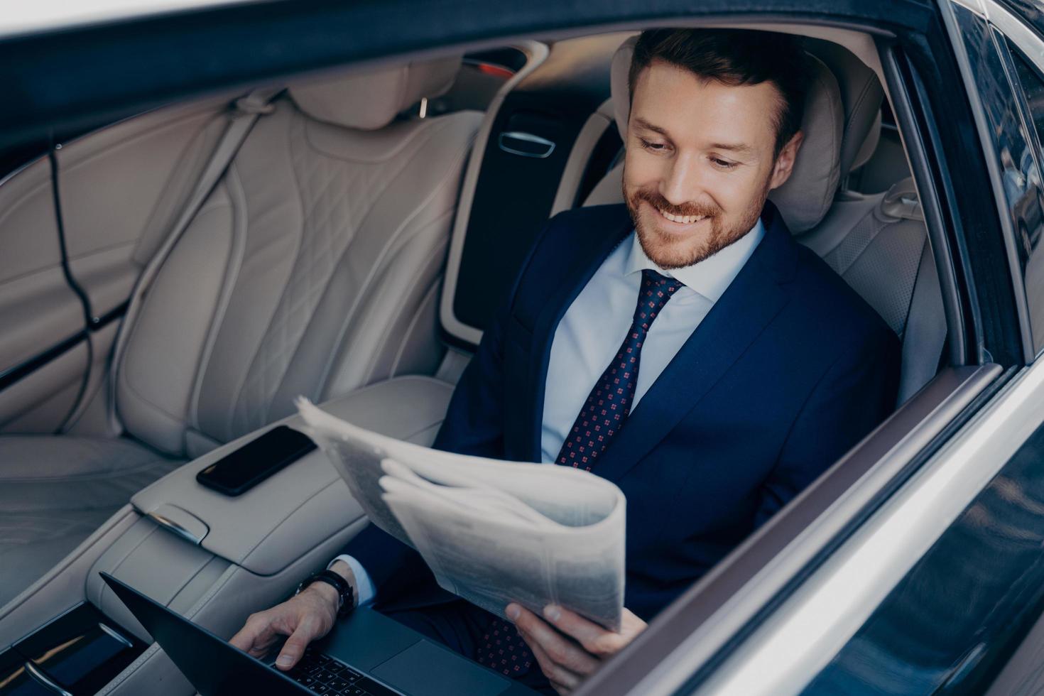 empresario relajado leyendo el periódico mientras viaja en limusina foto