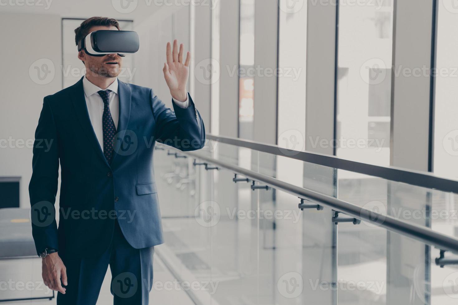 Excited office worker dressed in formal clothes managing business project through virtual reality photo