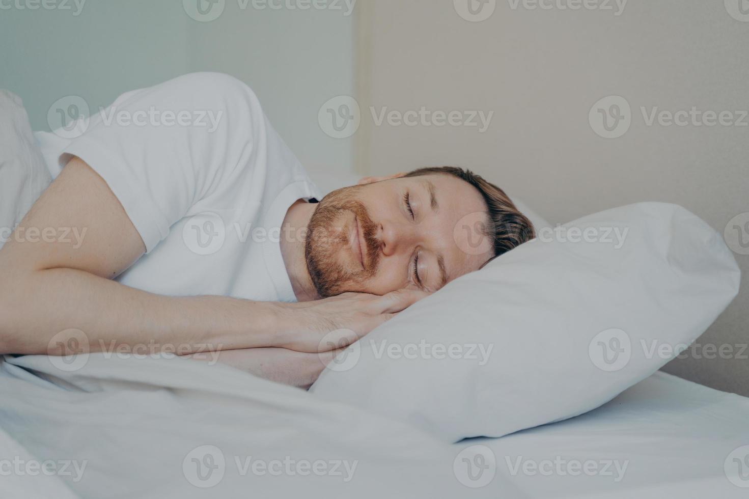 Close up view photo of bearded young male fall asleep in his bed