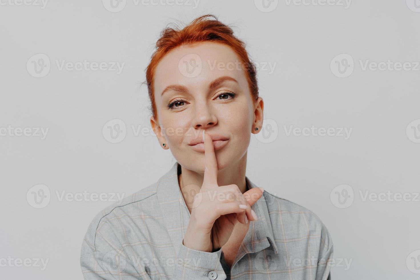 Caucasian female showing shh shush gesture, isolated on grey studio background photo