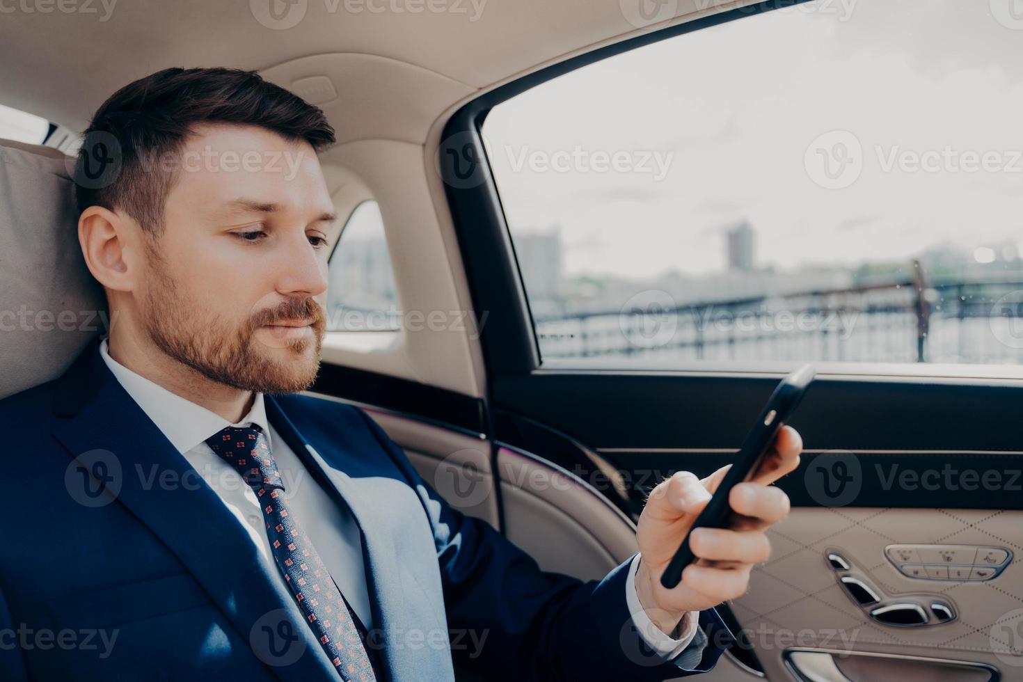 Investor checking his phone while riding in limousine photo