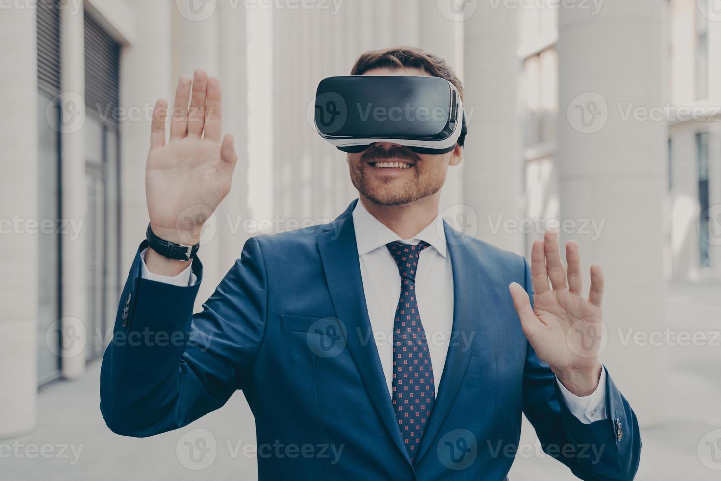 Businessman in suit trying out and experiencing virtual reality using mobile VR headset outdoors photo