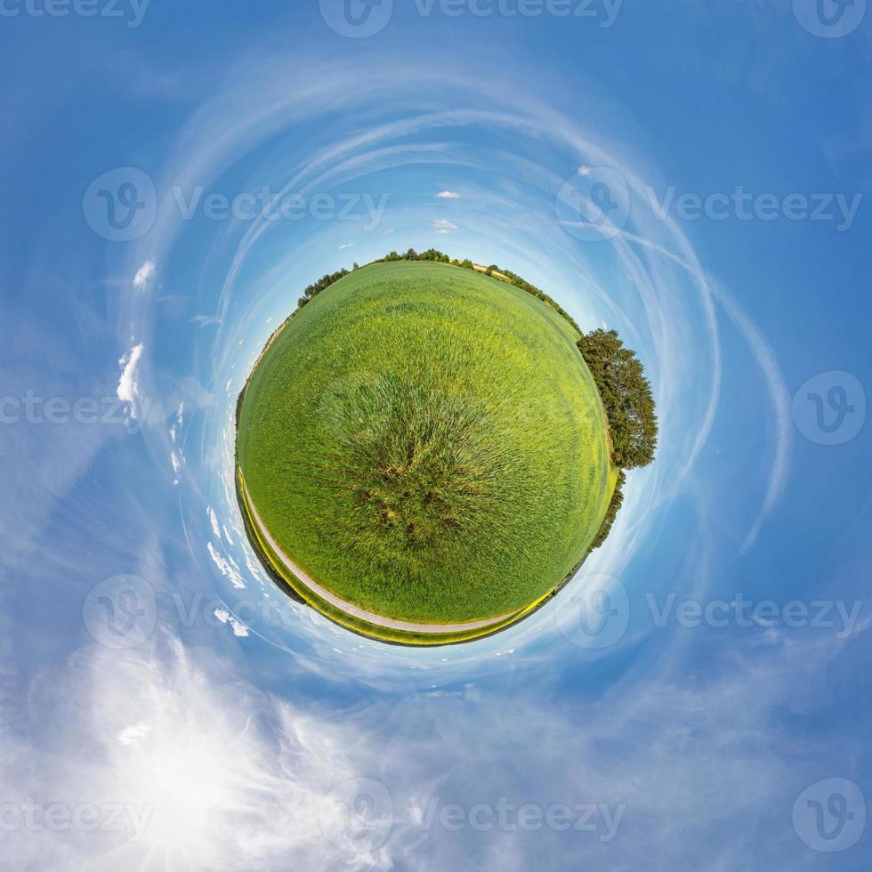 pequeño planeta vista esférica en un campo cerca de una carretera con colza en un día soleado foto