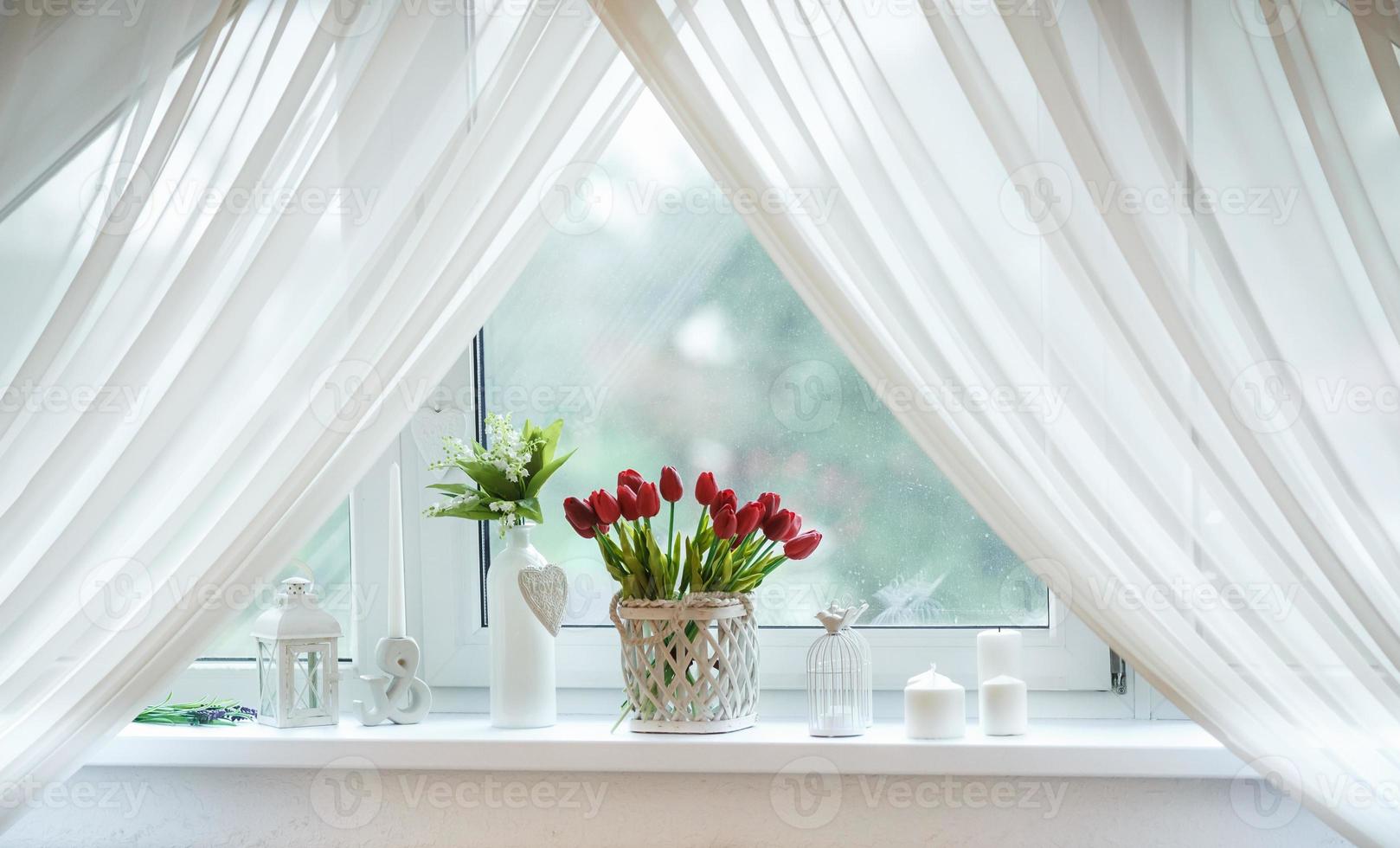red tulips and snowdrops in basket on the windowsill photo