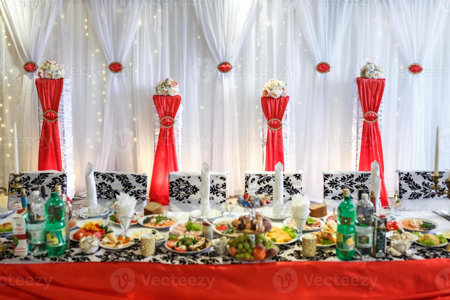 Decorated wedding table in the banquet hall. Table for newlyweds decorated with red ribbons photo