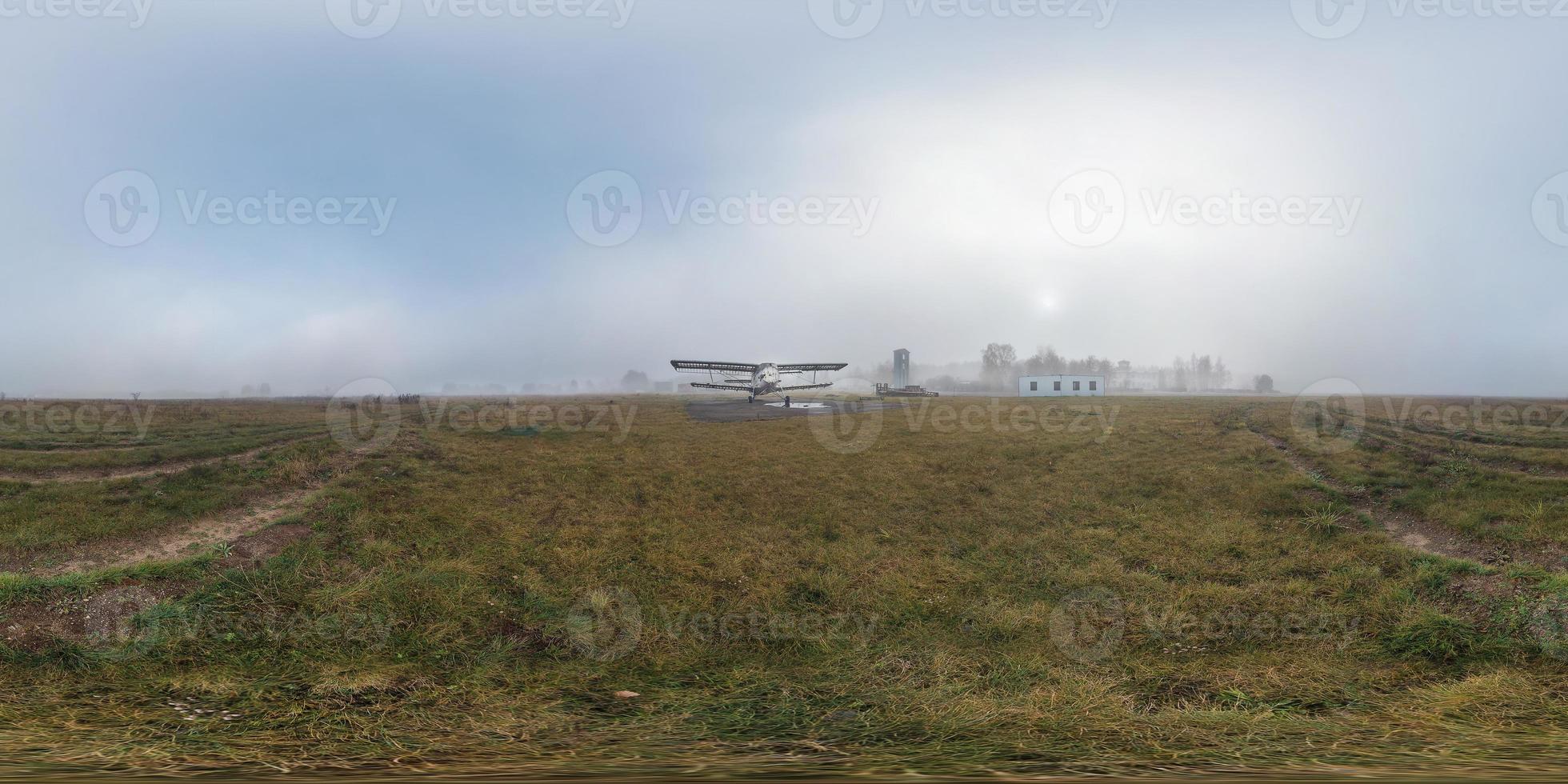 Foggy sunrise on meadow with old airplane. Full 360 equirectangular panorama. Skybox in virtual reality or 3D-graphics content as photorealistic background. photo