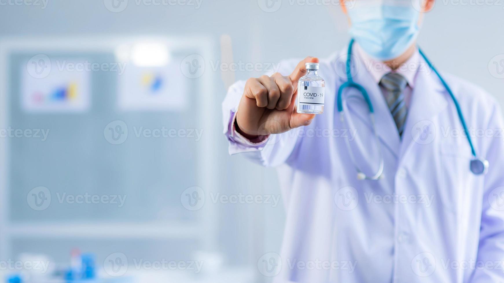 Close up of doctor hand holding Vaccines bottle used for cure or treatment trial, clinical research of Covid-19 Or corona virus in the office, Researching a vaccine that successfully cured the virus photo