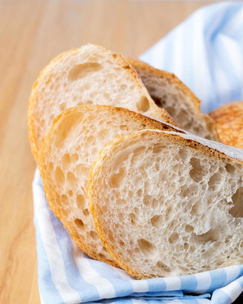 Fresh sliced baguette bread on wooden table. Healthy eating breakfast. photo