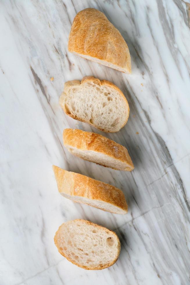 Fresh sliced baguette bread on marble table. photo