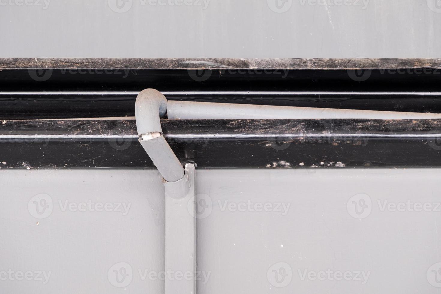 The electric wire in the plastic pipe for safety is along with the dirty metal frame. photo
