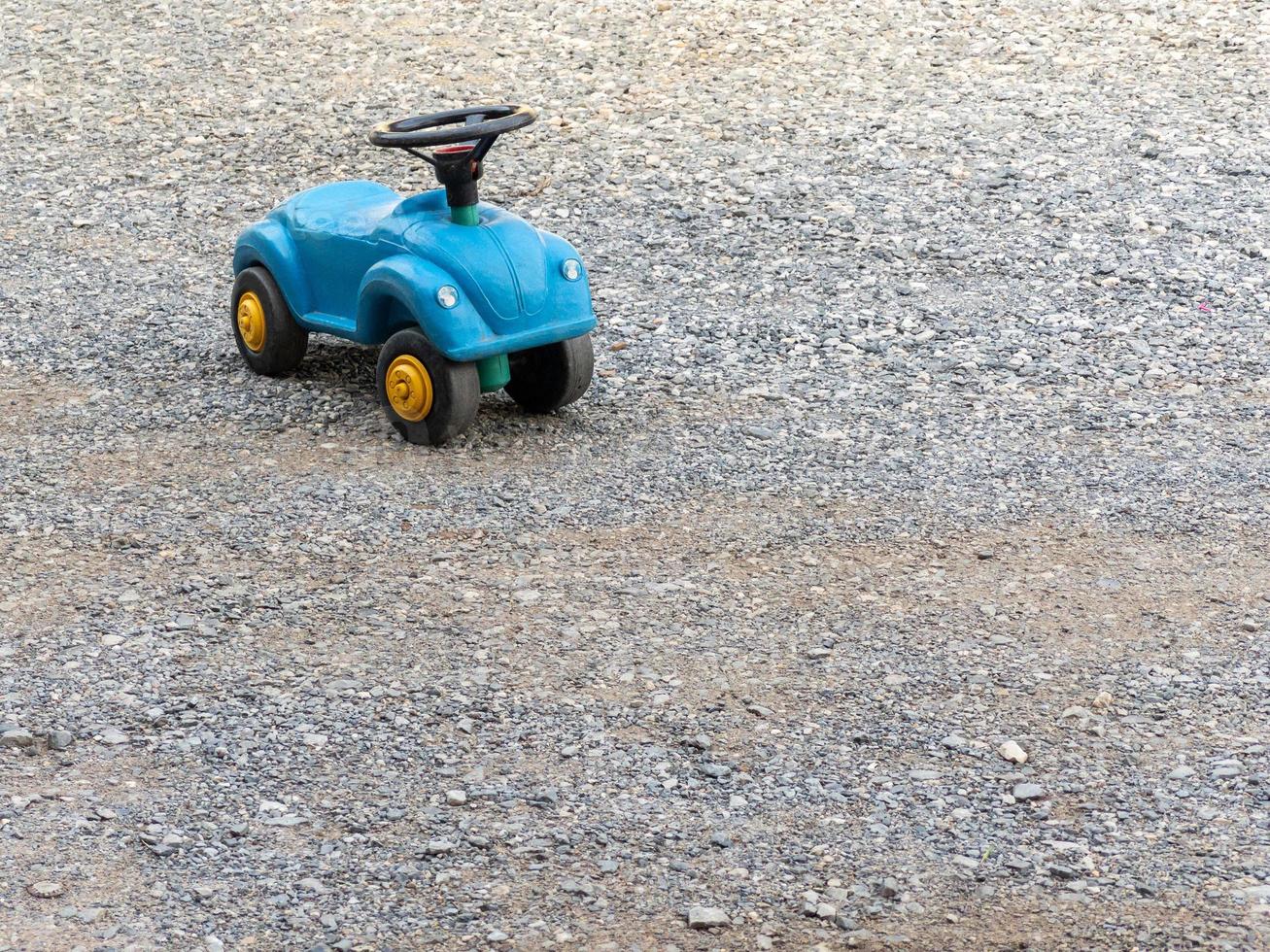 The plastic toy car with the black steering wheel on the ground. photo