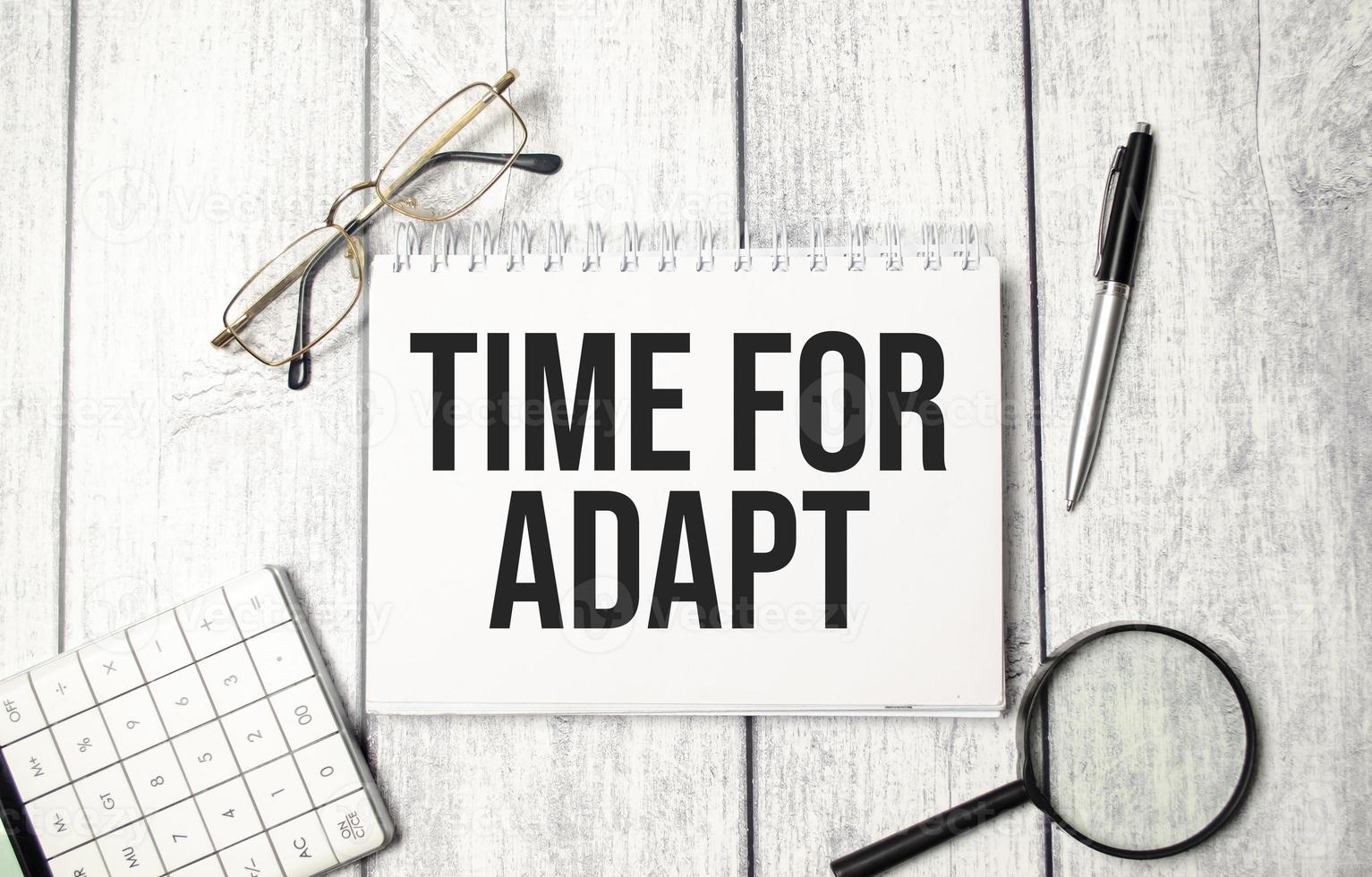 Word text TIME TO ADAPT on white paper notebook, business concept photo