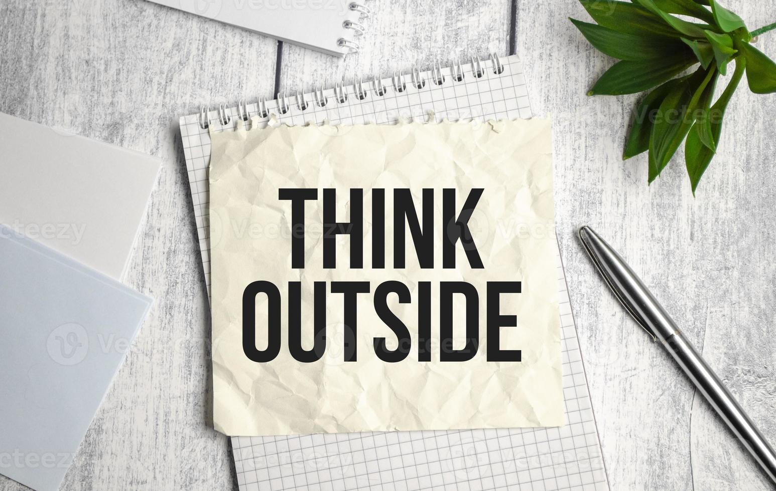 Blank sheet, pen and crumpled paper balls on grey table, flat lay. Text THINK OUTSIDE photo