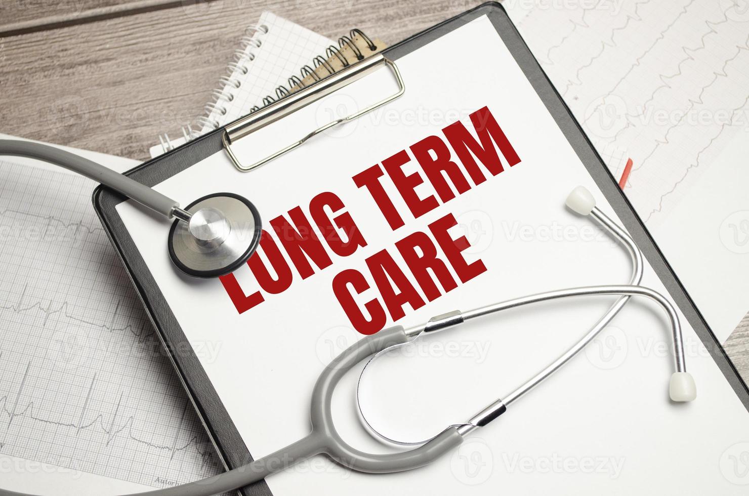 Medicine and health concept. On the table is a stethoscope, a diary and a notebook with the inscription - LONG TERM CARE photo