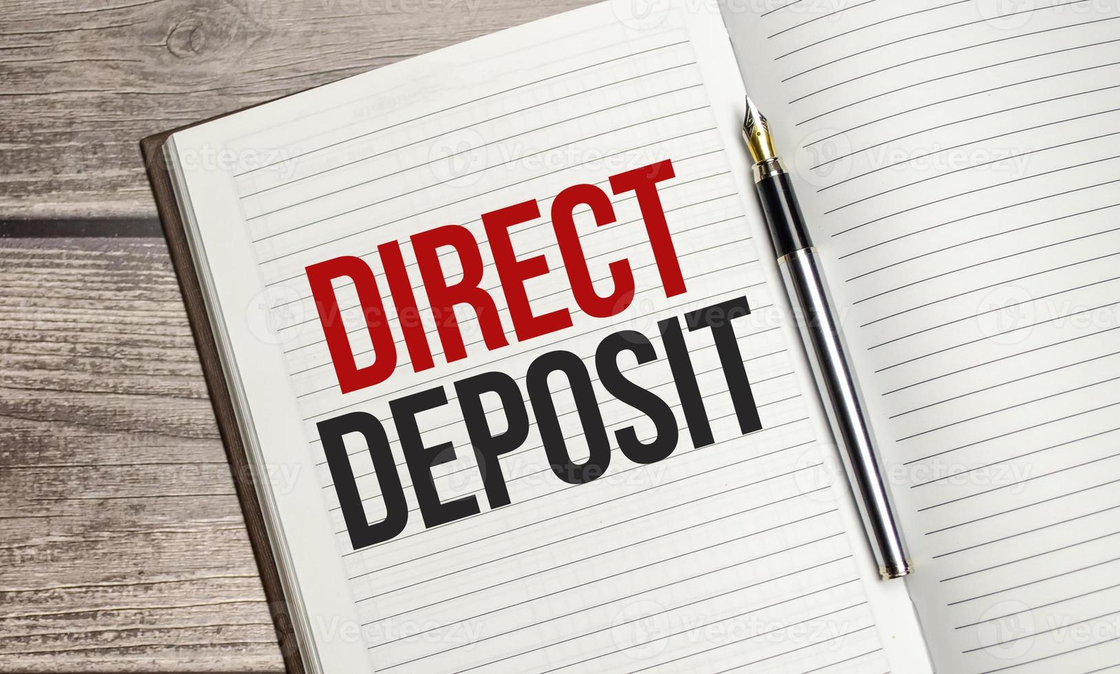 text direct deposit on brown diary with calculator, glasses on wooden background photo