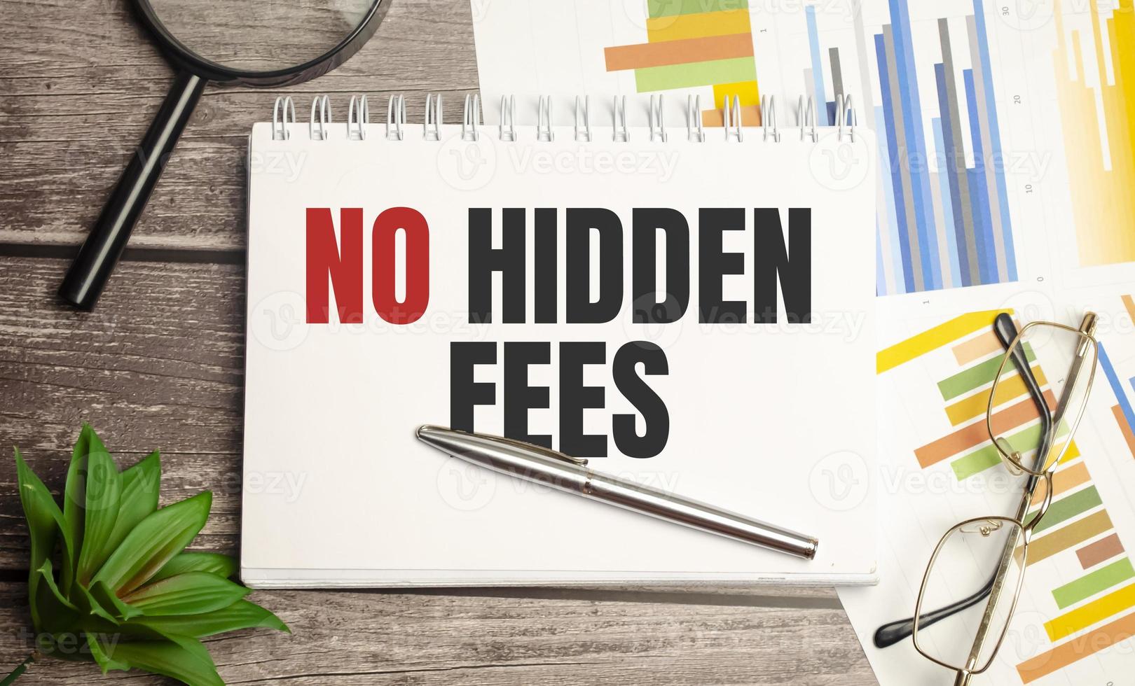 No Hidden Fees text written on black notebook with magnifying glass and a pen photo