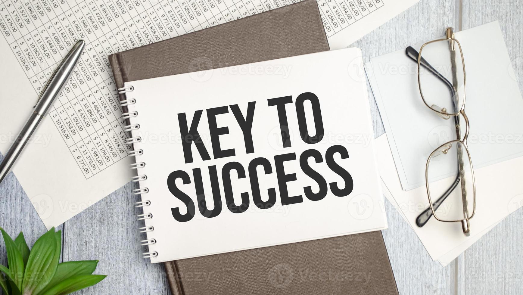 the word Key To Success, is written in a notebook lying on white table photo