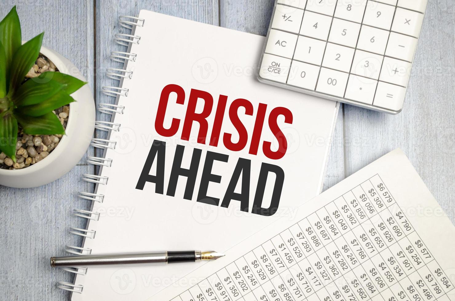 CRISIS AHEAD text on the paper sheet with paper and calculator photo