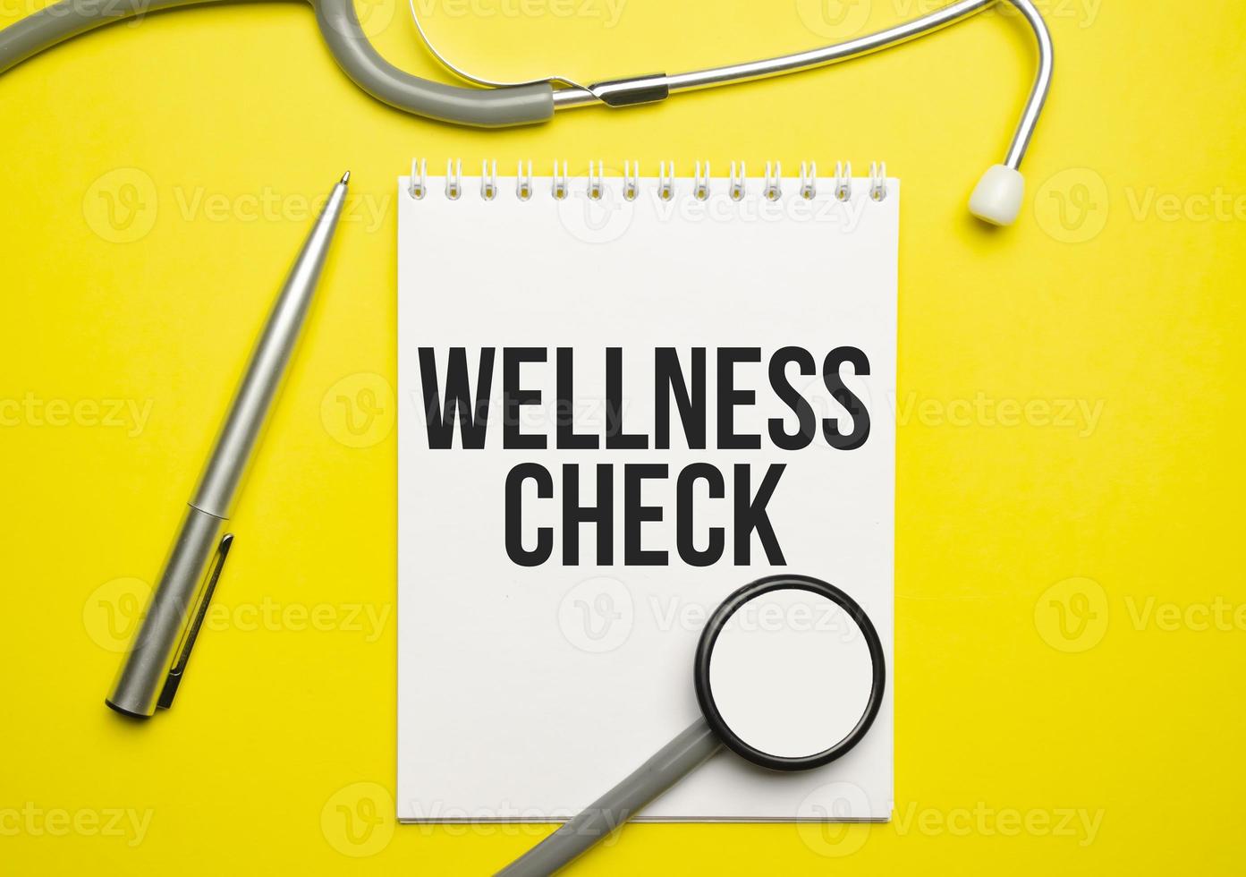 The word wellness check written on a white notepad on a yellow background photo