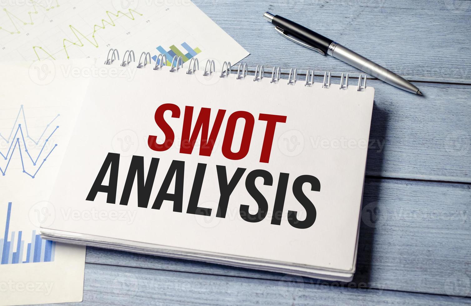 pen and a sheet of white paper with the text SWOT ANALYSIS photo