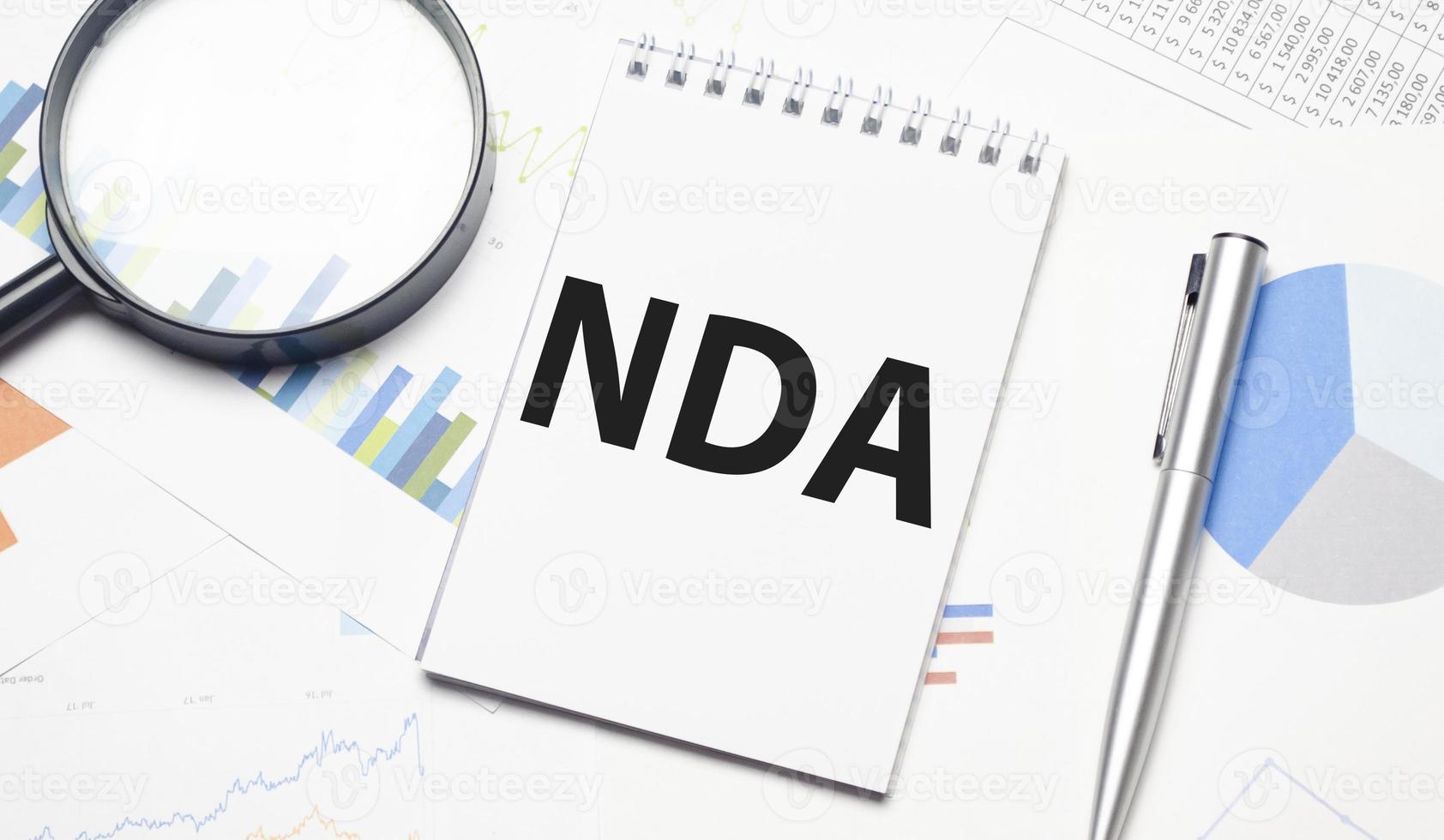nda word on notebook and pen, magnifier and charts photo