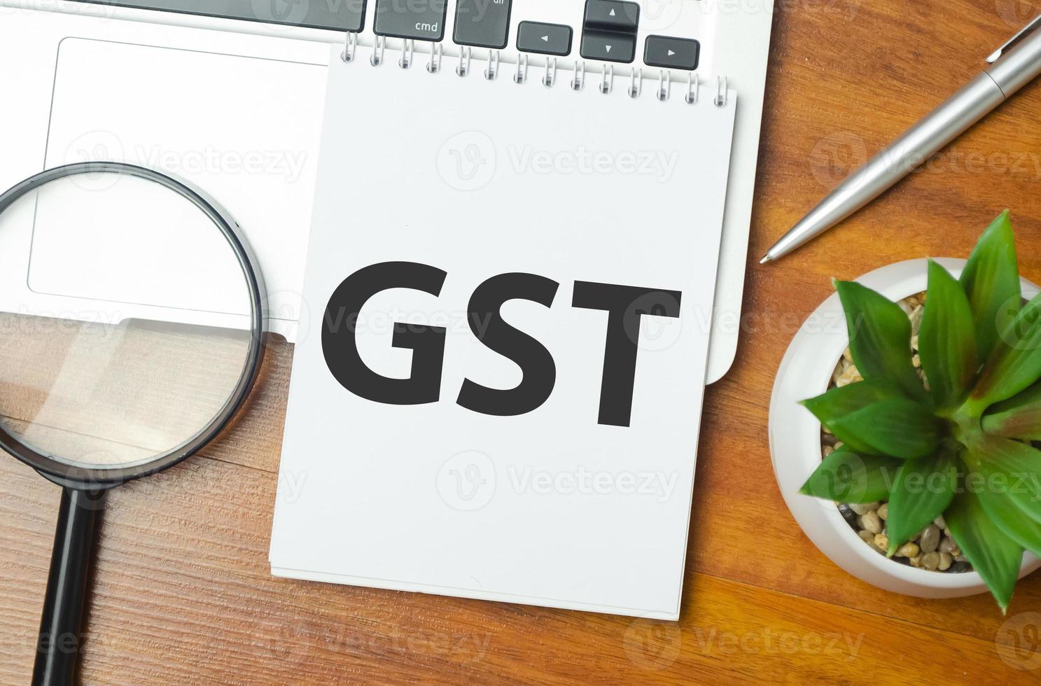 GST word on notepad and laptop on wooden background photo