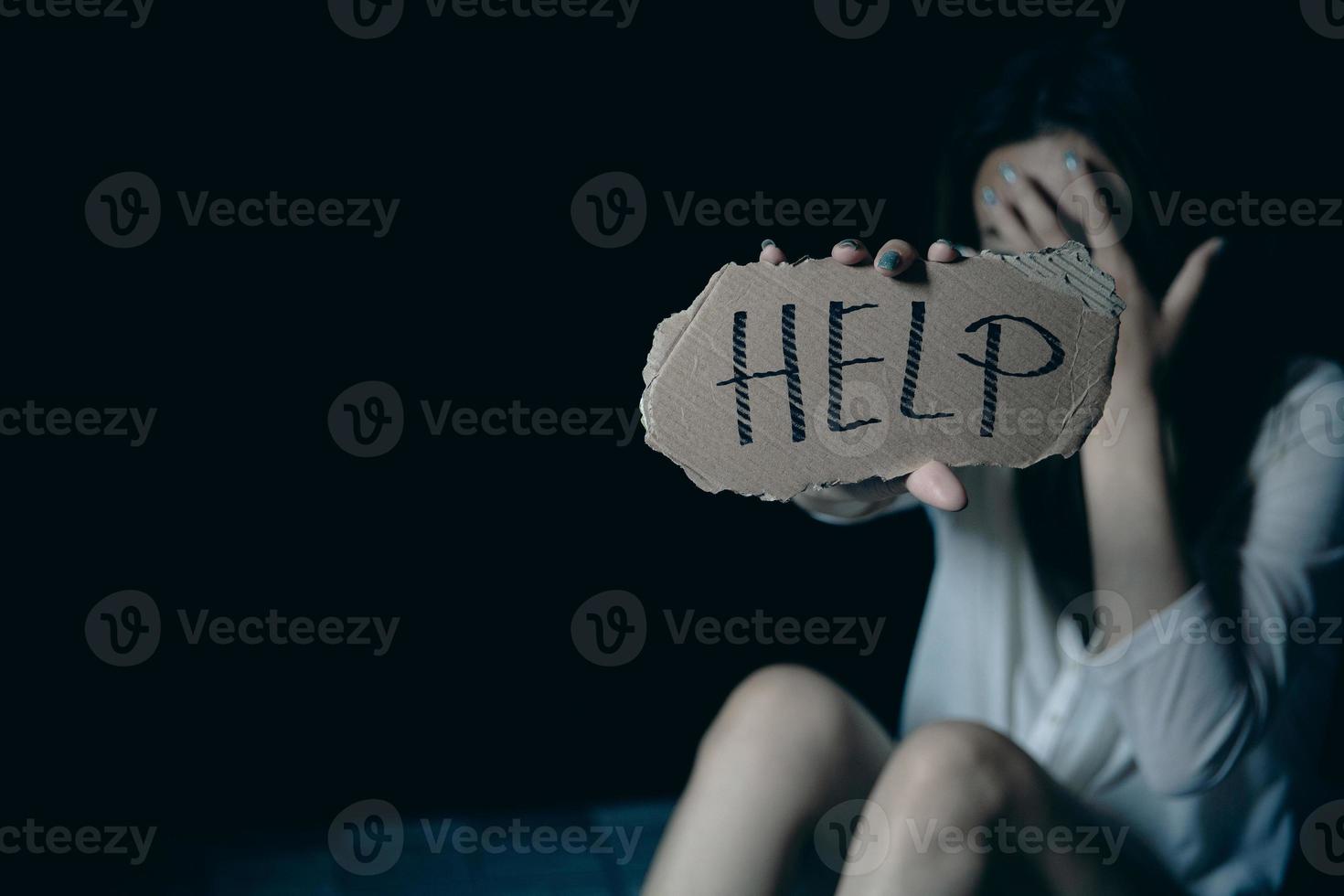 Scared and abused woman holding the paper with handwritten help sign photo
