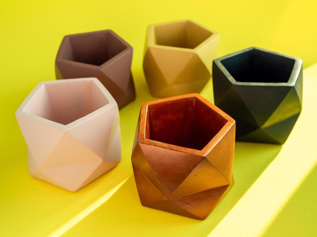 Colorful pentagon geometric concrete planters. Painted concrete pots for home decoration photo