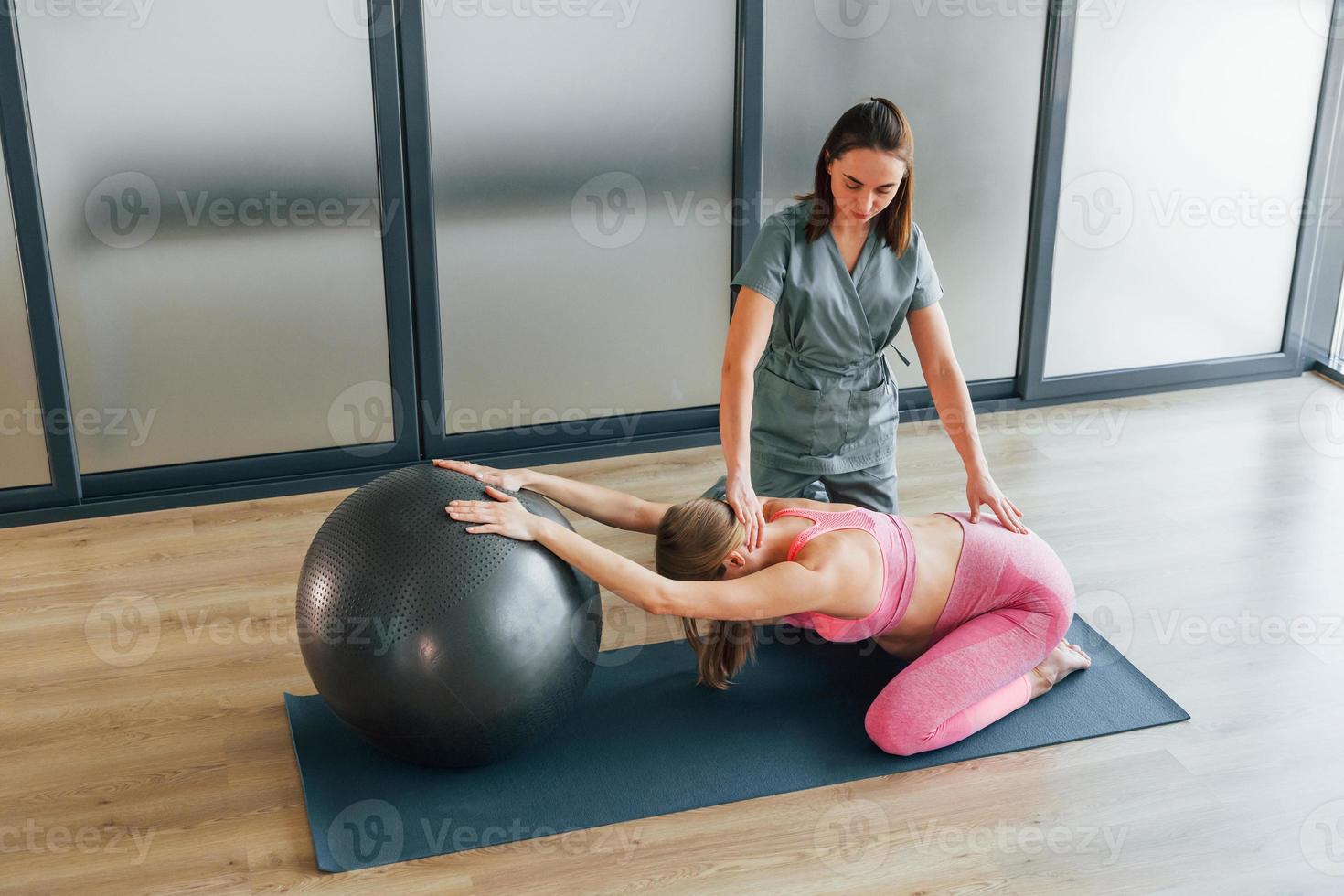 Stretching exercise. Woman is in health center getting help by doctor photo