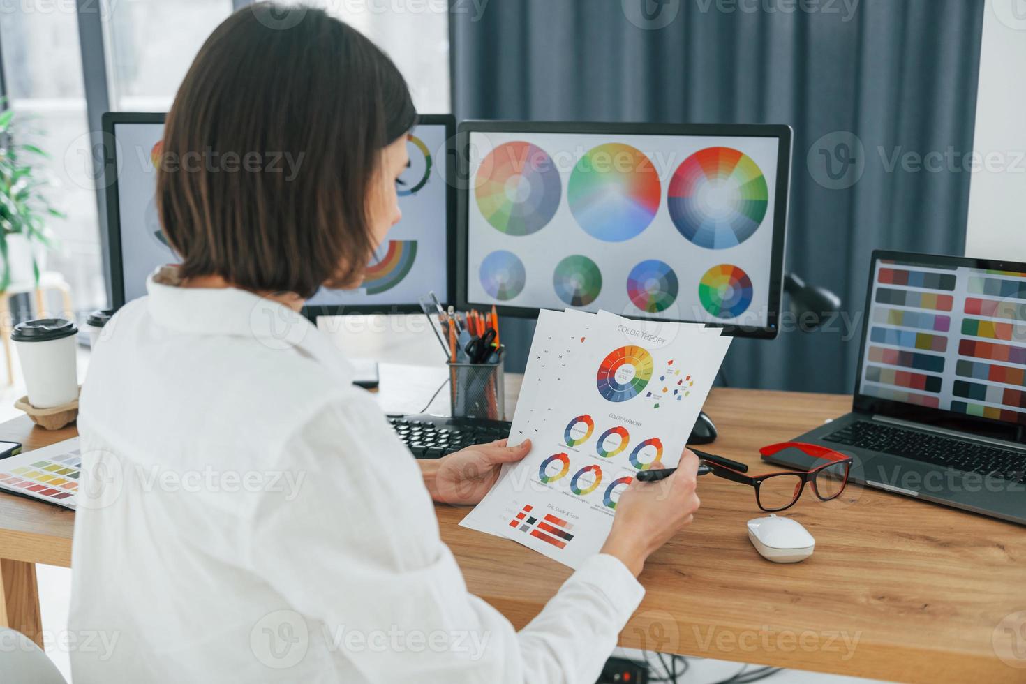 With paper. Female designer working in the office by using PC photo