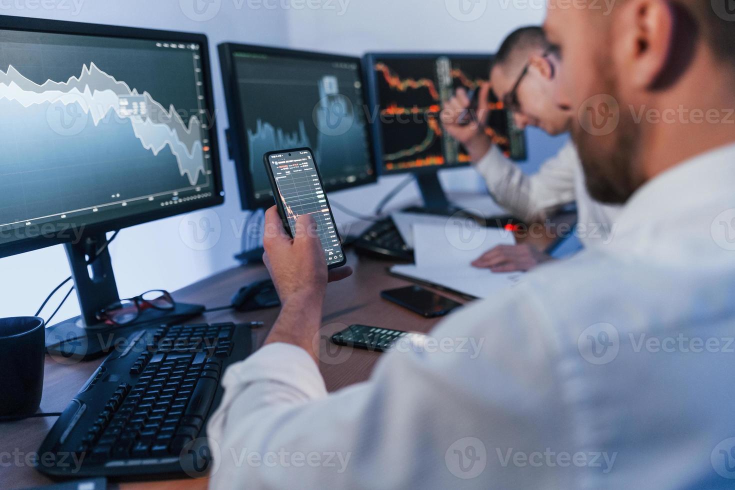 Using the phone. Two stock traders working in the office with exchange technology photo
