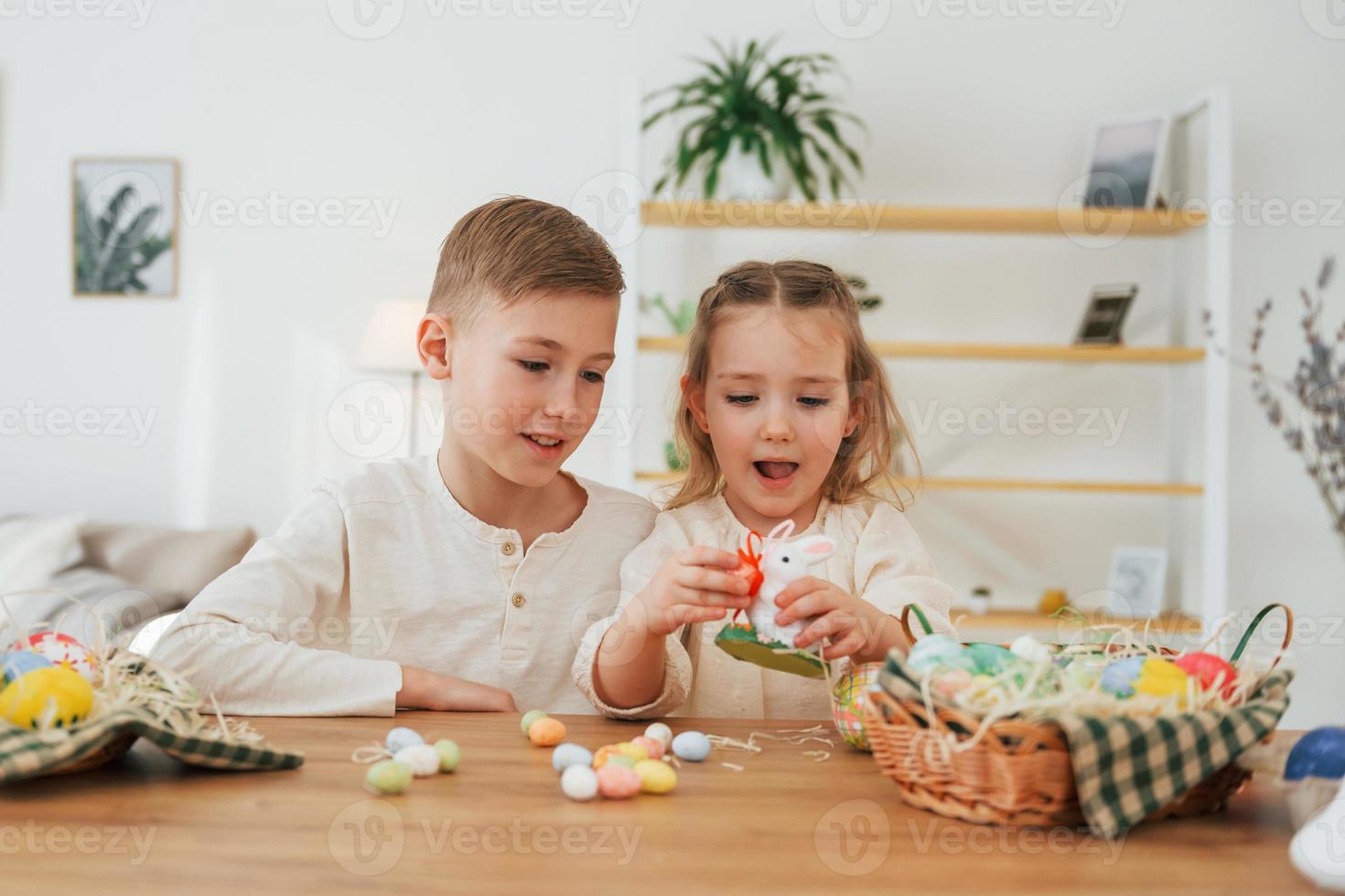 Sitting by the table. Happy little sister and brother celebrating Easter holidays together photo