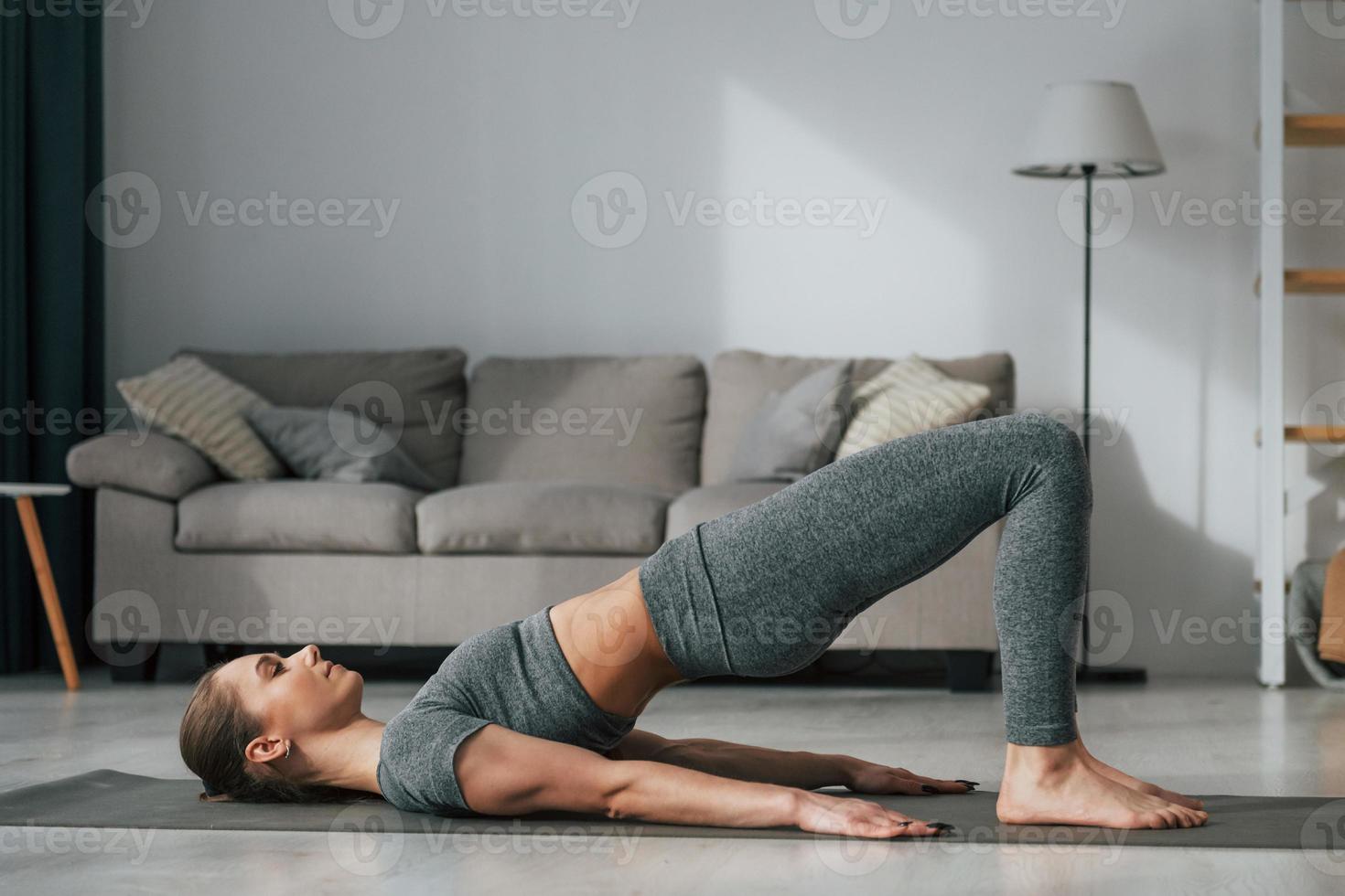 Stretching exercises. Young woman with slim body type and in yoga clothes is at home photo