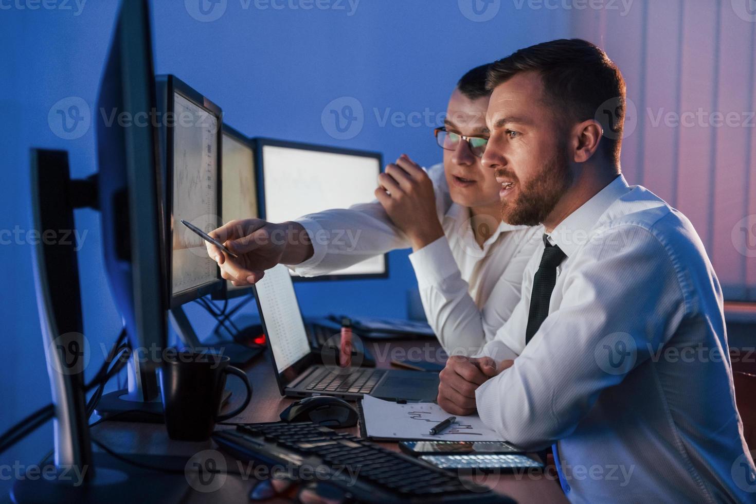 Active conversation. Two stock traders working in the office with exchange technology photo