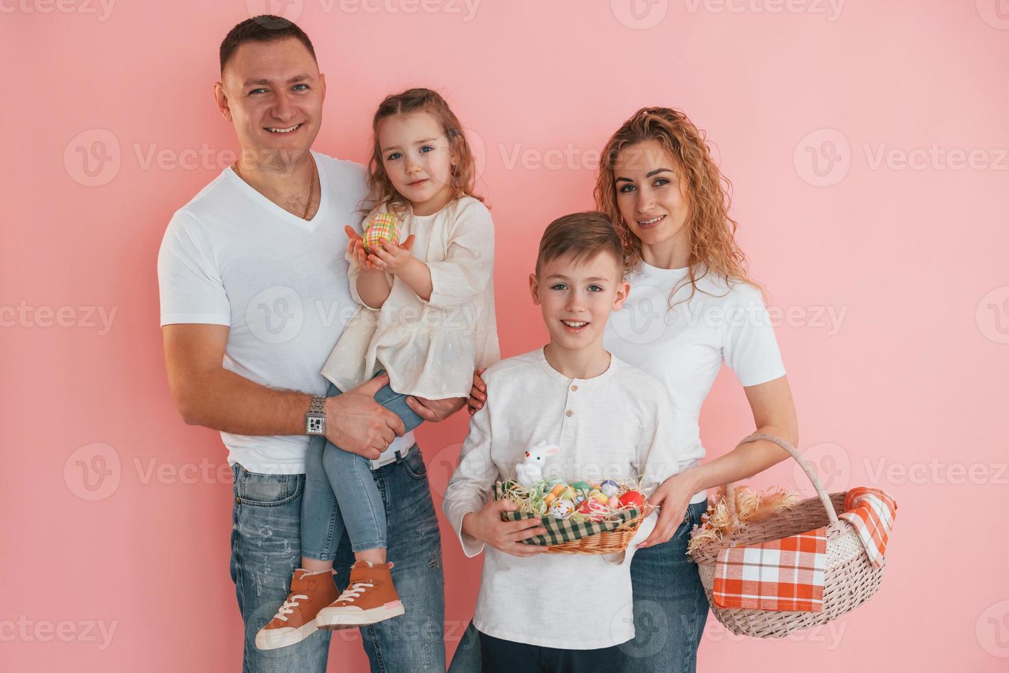 Standing against pink background. Happy family celebrating Easter holidays together photo