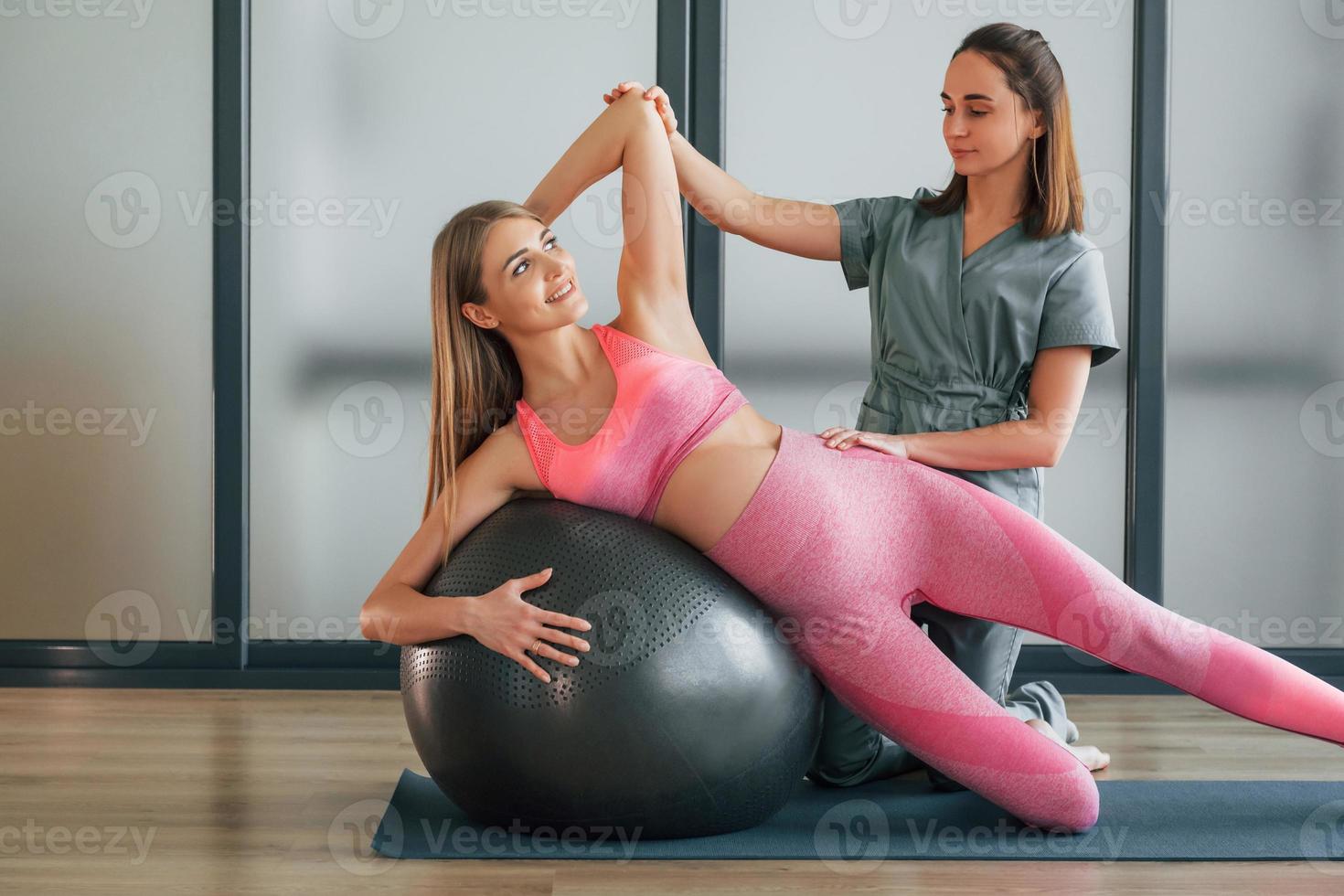 usando pelota de fitness. la mujer está en el centro de salud recibiendo ayuda del médico foto