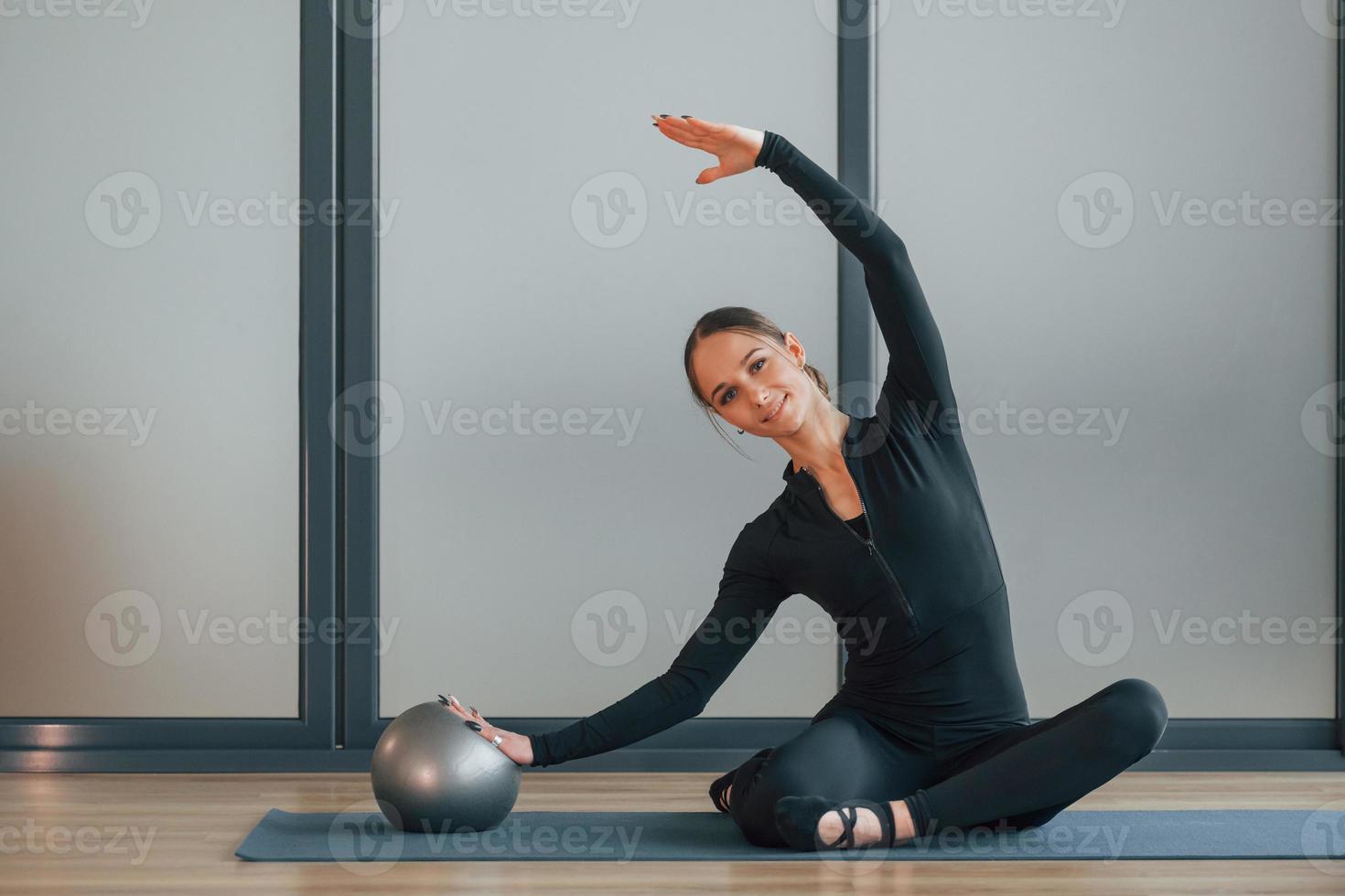 sentado en la estera de yoga. mujer con ropa deportiva está en el estudio foto