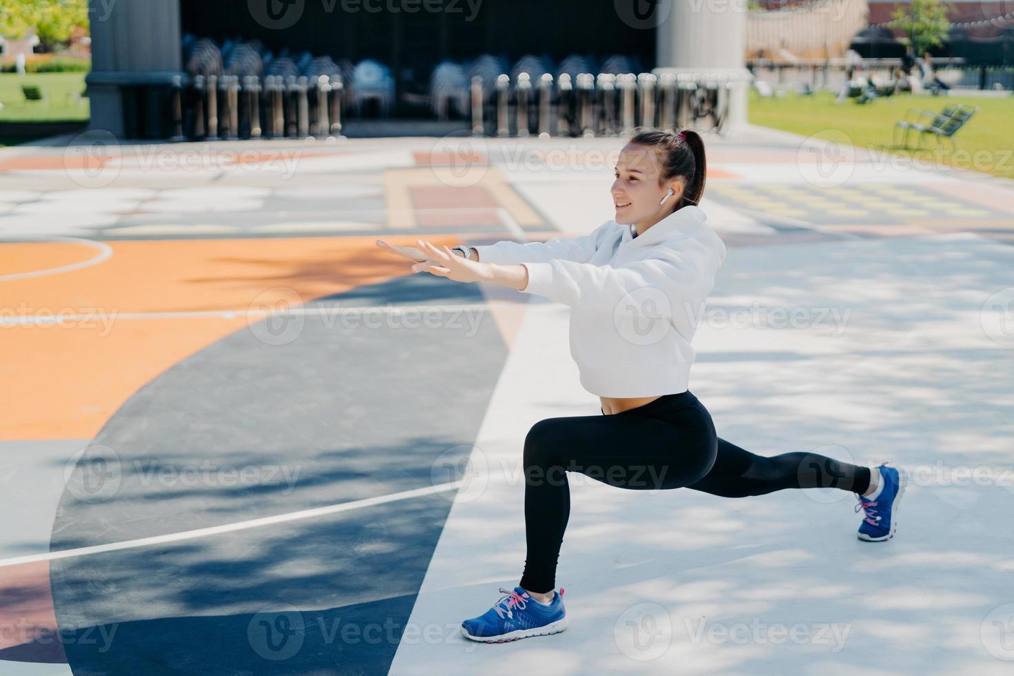 una foto horizontal de una mujer deportiva motivada estira las piernas y  los brazos hace ejercicios