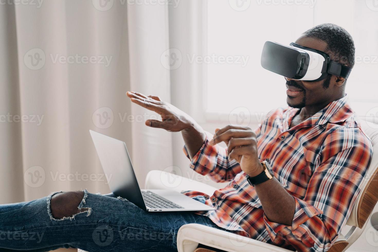 African american man in virtual reality glasses view purchase online at laptop. Tech, e-commerce photo