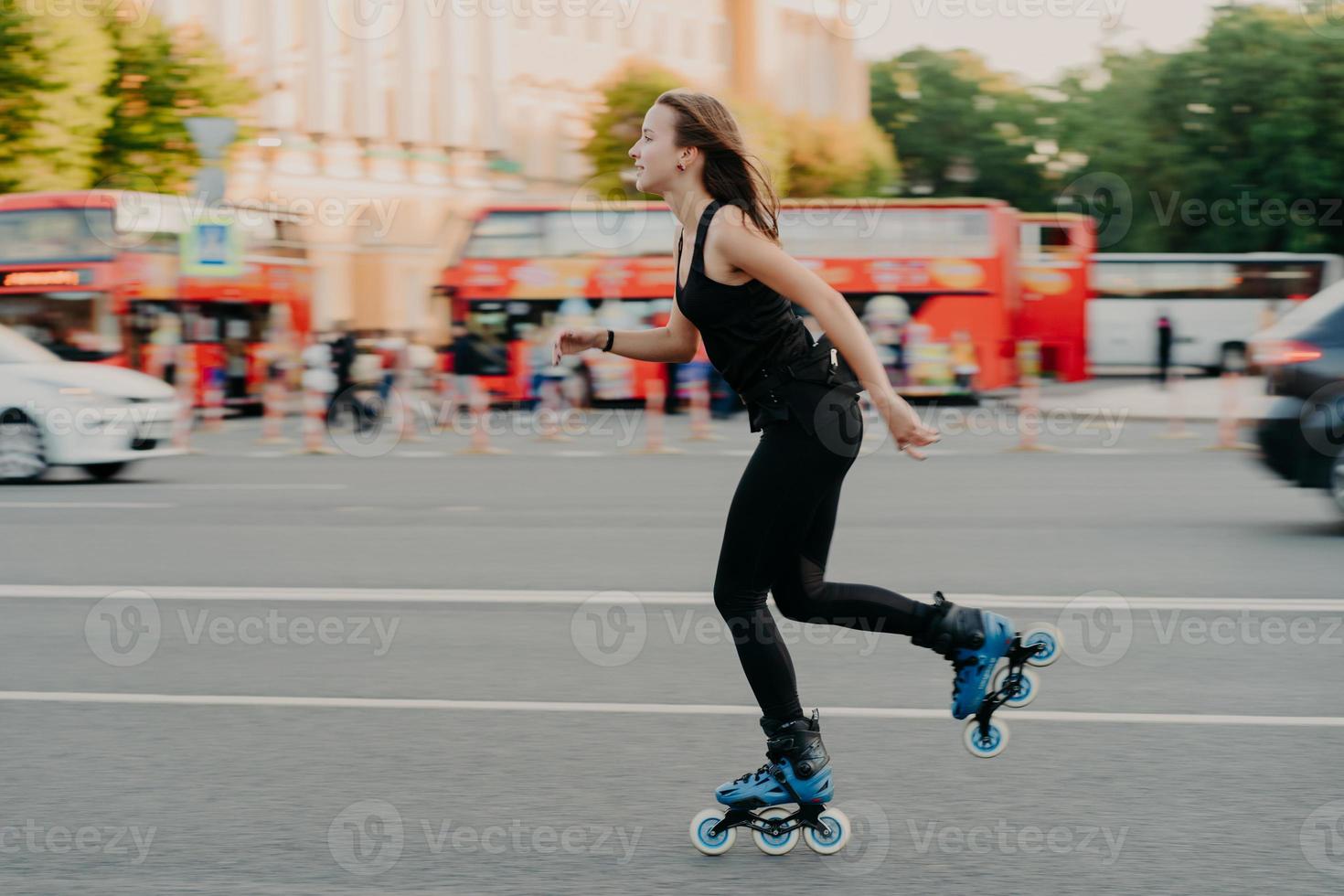 Outdoor activities for being healthy and fit. European woman in good physical shape rides on rollers rolleblades on inline skates dressed in active wear has active rest. Sporty lifestyle concept photo