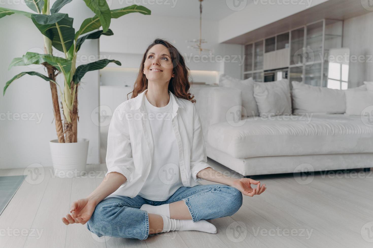 Peace of mind and mental health concept. Young european woman practicing yoga on floor and smiling. photo